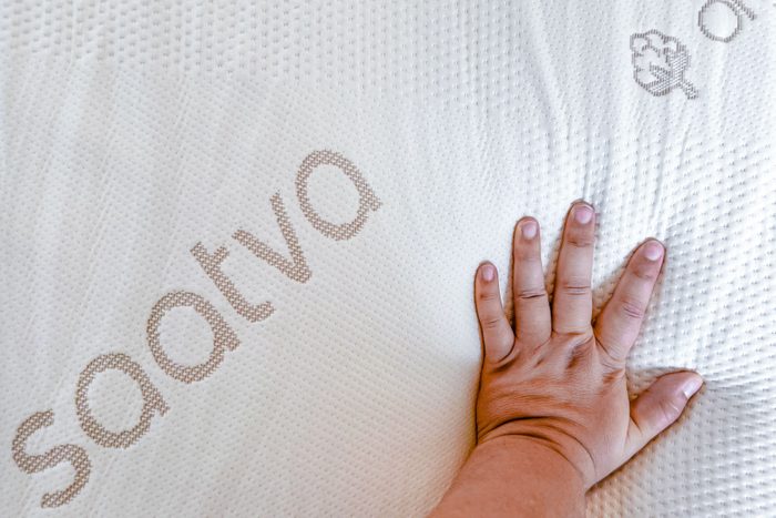 Hand pressing on the Saatva Graphite Memory Foam Mattress Topper