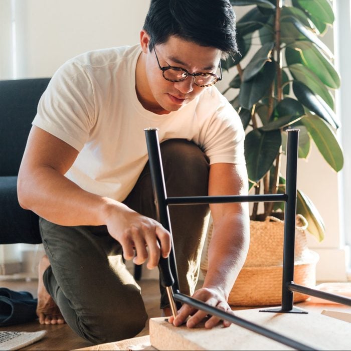 Focused Young Man Assembling Furniture At Home